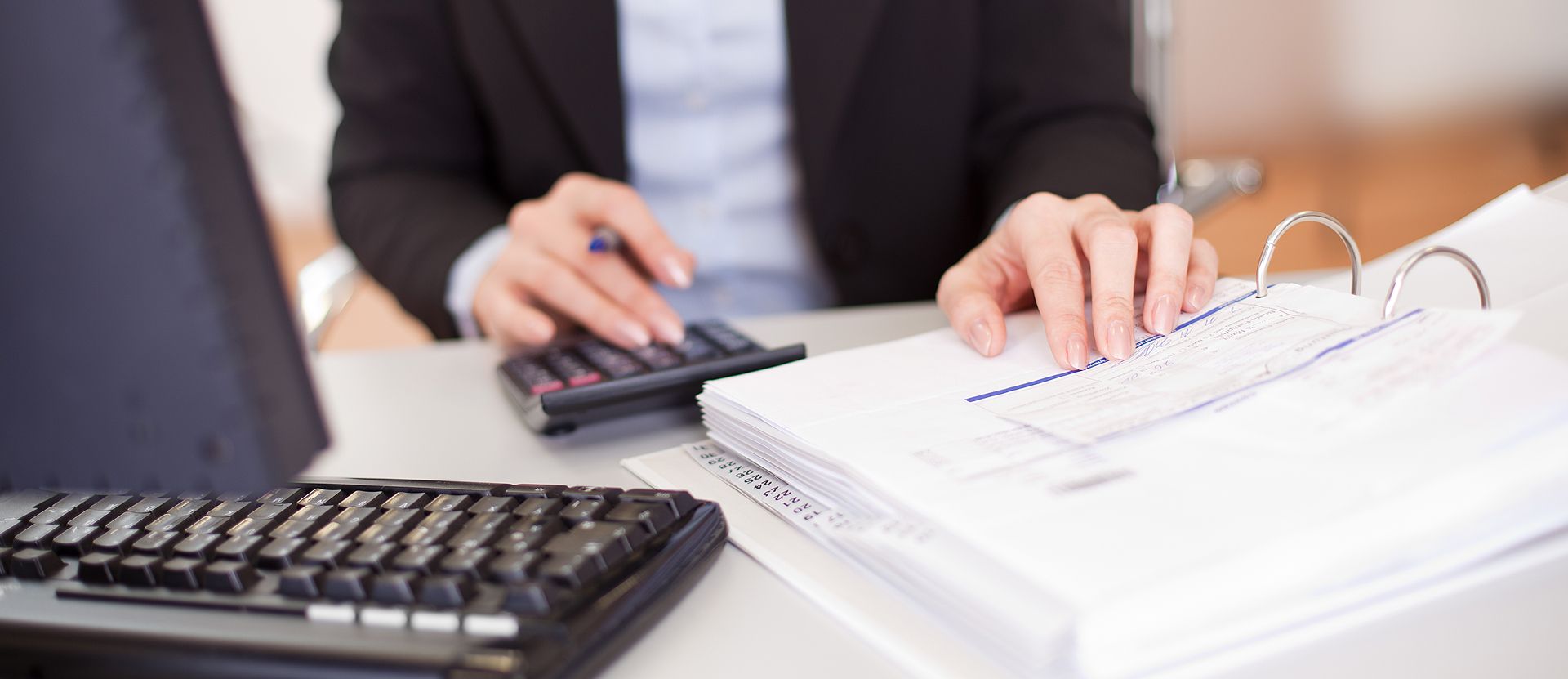 Frau gibt am Taschenrechner Zahlen ein und überprüft Belege